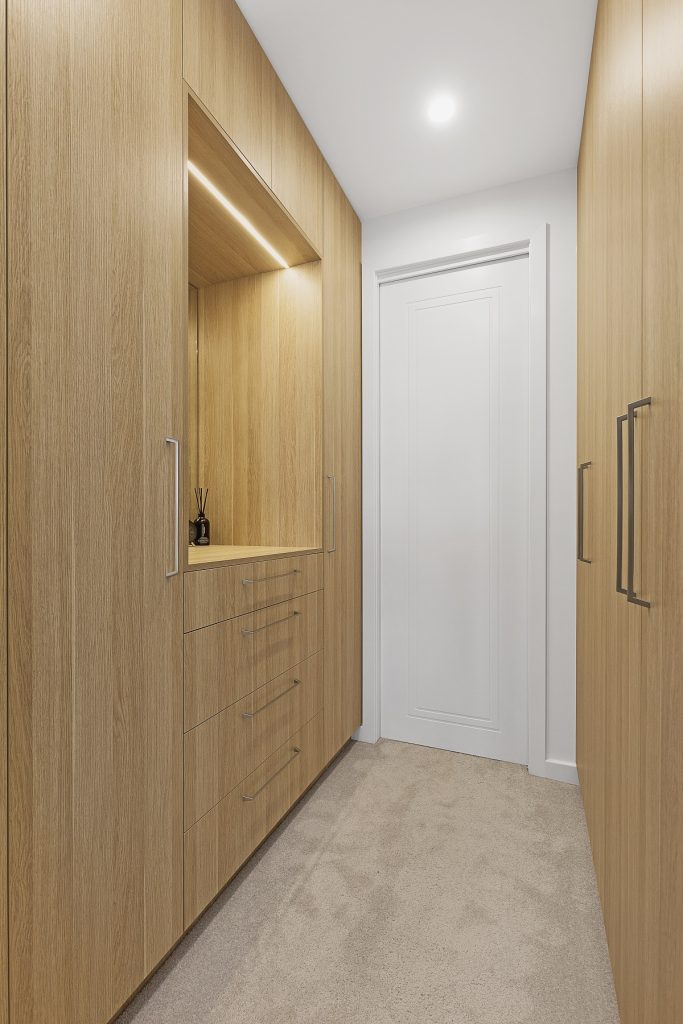 Walk-in wardrobe in a Timber Laminate finish with built-in LED lights and mirror - Chipping Norton, Sydney