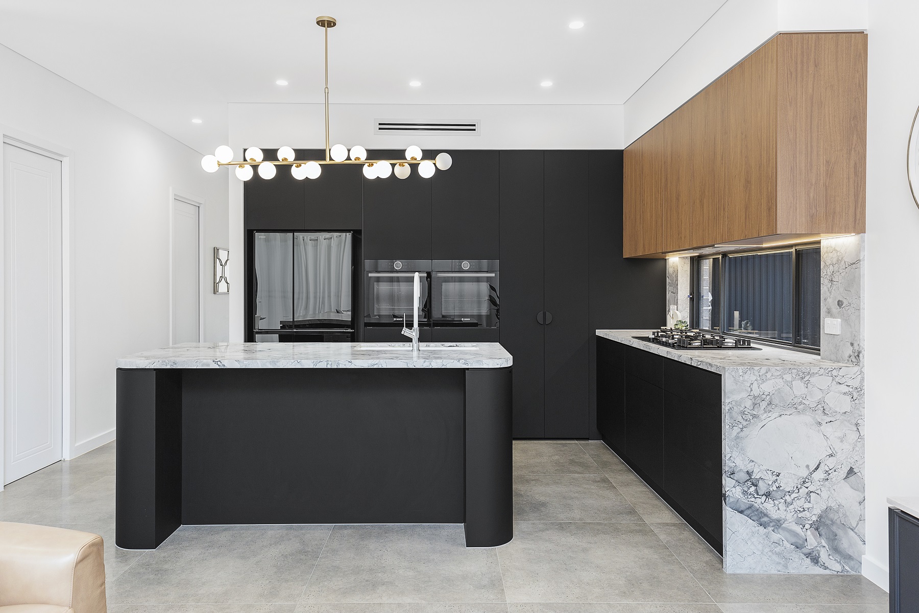 Chipping Norton, Matt black kitchen featuring Super White Stone benches and a curved edge island