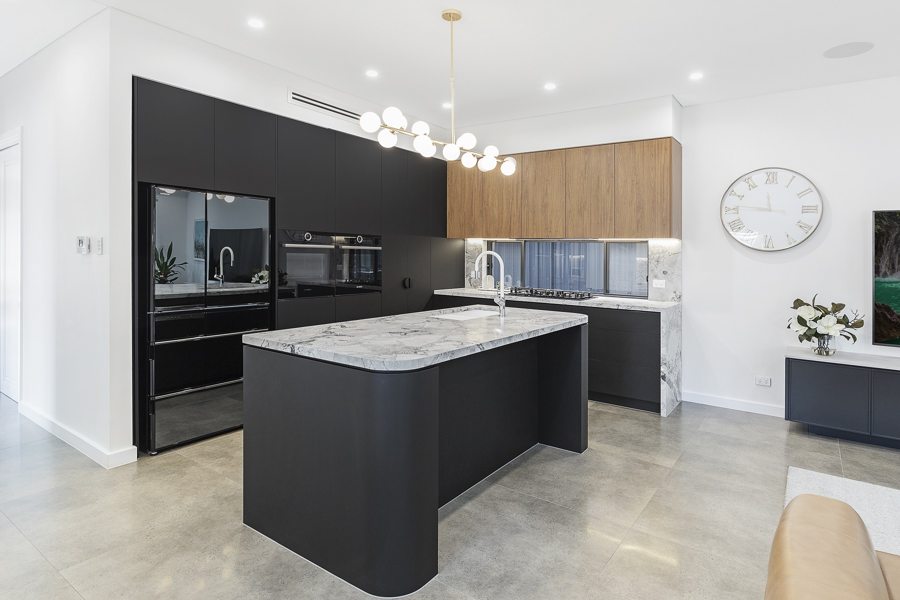 Chipping Norton, Matt black kitchen featuring Super White Stone benches and a curved edge island