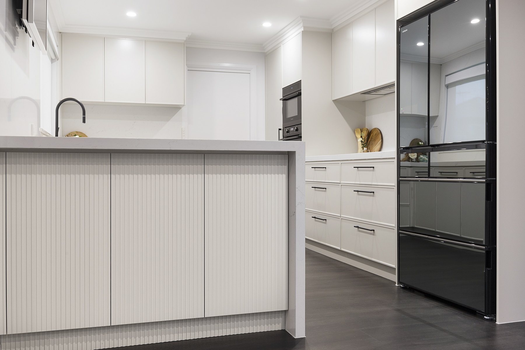 Moorebank, Polyurethane Thin Shaker kitchen with a Quantum Quartz stone benchtop and splashback in Michelangelo and featuring a fluted paneled breakfast bar