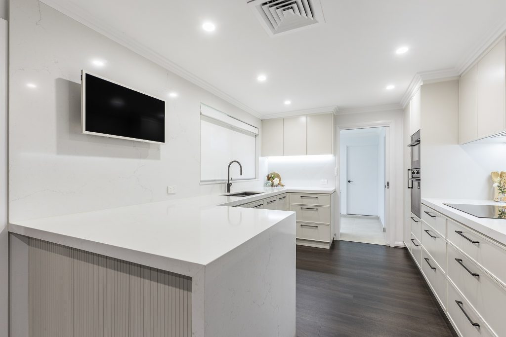 Moorebank, Polyurethane Thin Shaker kitchen with a Quantum Quartz stone benchtop and splashback in Michelangelo and featuring a fluted paneled breakfast bar